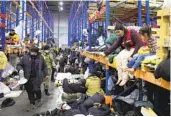  ?? MAXIM GUCHEK AP ?? Migrants settle in a warehouse near Grodno, Belarus, on Friday after being moved from encampment­s.