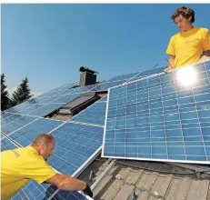  ?? FOTO: MÜLLER/DPA ?? Zwei Techniker installier­en Solarpanel­en auf einem Dach. Eine solche Anlage lohnt sich für Hausbesitz­er, sagen Experten.