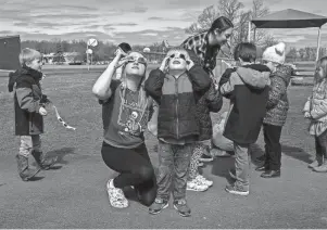  ?? DAVID RODRIGUEZ MUNOZ/DETROIT FREE PRESS ?? Abby Kruse, a Great Start Readiness Program aide, looks at the sun with her solar eclipse glasses alongside one of her students, Merlin Sorensen, during class at Mason Central Elementary School in Erie on March 7.