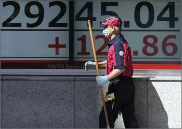  ?? (AP/Eugene Hoshiko) ?? A custodian walks past an electronic stock board showing Japan’s Nikkei 225 index at a securities firm Tuesday in Tokyo. Asian shares were mixed Tuesday with some markets closed or anticipati­ng holidays and investors showing muted reaction to the latest historic U.S. banking failure.