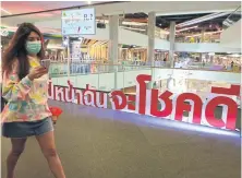  ?? SOMCHAI POOMLARD ?? A woman wears a face mask while shopping at Seacon Square shopping mall in Bangkok.