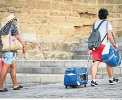  ?? JULIO GONZÁLEZ ?? Dos turistas se desplazan con sus maletas delante de la Catedral gaditana.
