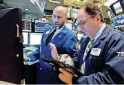  ?? [AP PHOTO] ?? Specialist Meric Greenbaum, left, and trader James Conti work on the floor of the New York Stock Exchange.