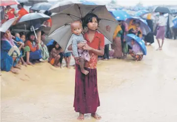  ??  ?? Rohingya refugees queue in the rain to receive food at Kotupalang refugee camp near Cox’s Bazar, Bangladesh. — Reuters photo