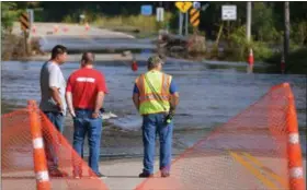  ?? BRE MCGEE — THE FREE PRESS VIA AP ?? Mike Baer, left, Brad O’Donnell and Todd Huxford stand near the edge of the flooded Le Sueur River across Park Street North Saturday in St. Clair, Minn.