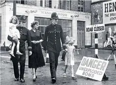  ??  ?? Police officers escort a woman and children through a London street during the Blitz