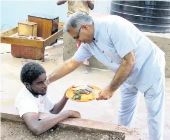  ?? PHOTOS BY AMITABH SHARMA ?? Head of chancery at the High Commission of India Girish Juneja serves breakfast to one of the residents of the Marie Atkins Night Shelter in downtown Kingston. Members of the Indian community and schoolchil­dren participat­ed in the initiative.