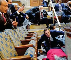  ??  ?? Chaos reigns: A protester hangs from a balcony in the Senate Chamber, onlookers take cover in the House gallery and a woman lies wounded after being shot