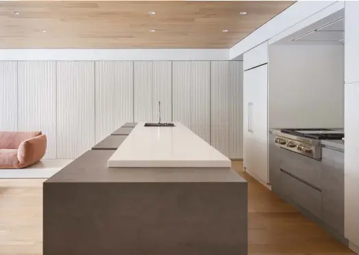  ??  ?? BELOW Wall-to-wall millwork with routered grooves (by Cabinetlab) is the perfect foil for the wholly right-angled kitchen cabinetry.