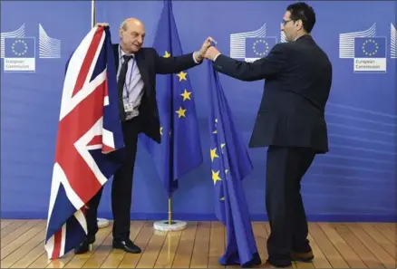  ?? GEERT VANDEN WIJNGAERT, THE ASSOCIATED PRESS ?? Members of protocol adjust the British and EU flags at EU headquarte­rs in Brussels. On Monday, the European Commission said it has been informed in advance of Britain’s plans to trigger its exit from the EU on March 29 and stands ready to help launch...