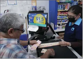  ?? (AP/Wilfredo Lee) ?? Mariano Velasquez (left) buys lottery tickets from Mirta Herrera, Monday at the Presidente Supermarke­t in the Little Havana neighborho­od of Miami.