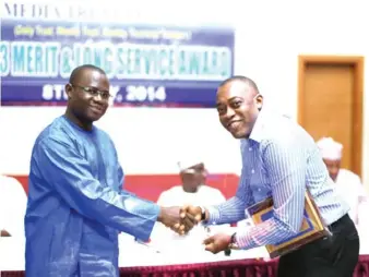  ?? PHOTOS: GODSWILL AYEMOBA ?? Recipient of the Chairman’s Excellence award, Charles Mere (right) being presented with his prize by the Managing Director/Chief Operating Officer, Ishaq Ajibola, during the Media Trust Limited Long Service and Merit Award in Abuja yesterday.