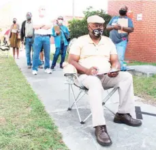  ??  ?? Richard Williams sits in a folding chair, filling out paperwork, as he waits in line to vote early in Savannah, Ga., on Wednesday, Oct. 14, 2020. Black people are going to the polls by the thousands and waiting in lines for hours to vote early in Georgia. (Photo by Russ Bynum, AP)