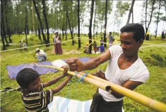  ?? Munir Uz Zaman / AFP / Getty Images ?? Rohingya Muslim refugees from Myanmar build makeshift shelters after crossing the border into the Bangladesh­i town of Teknaf. About 300,000 Rohingya have fled in the past two weeks.