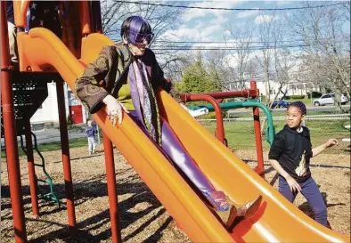  ?? ?? U.S. Rep. Rosa DeLauro rides down a playground slide Friday during a visit to the afterschoo­l program at Sterling House Community Center in Stratford, shown at left.