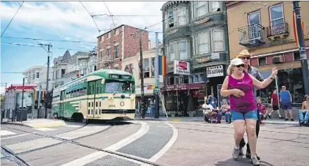  ?? JUSTIN FRANZ/THE WASHINGTON POST ?? A streetcar painted in vintage green and cream livery passes people square dancing in the famous Castro District of San Francisco.