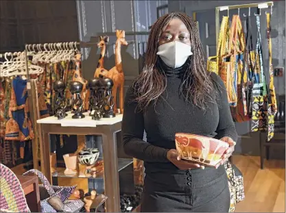  ?? Photos by Lori Van Buren / Times Union ?? Hotalou “Justine” Goldberg holds a unity bowl, one of the most popular items, as she stands in her store West Africa Treasures in Crossgates Mall.