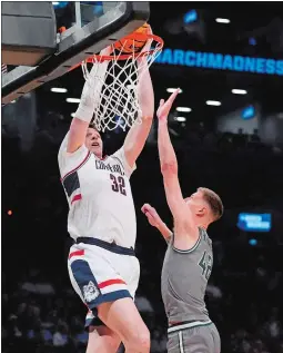  ?? FRANK FRANKLIN II/AP PHOTO ?? UConn’s Donovan Clingan (32) dunks the ball in front of Stetson’s Treyton Thompson (42) during the second half of a first-round game in the NCAA tournament on Friday in New York. UConn won 91-52.