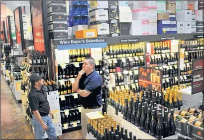  ?? MARLA BROSE/JOURNAL ?? Wine and liquor distributo­rs Manuel Orellana, left, and Lawrence Chavez, right, watch as Total Wine & More workers finish readying the new store at 10420 Coors Bypass NW.