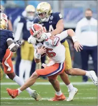  ?? Jeff Siner / Associated Press ?? Notre Dame safety Kyle Hamilton grabs the face mask of Clemson quarterbac­k Trevor Lawrence during the Atlantic Coast Conference championsh­ip game Dec. 19.