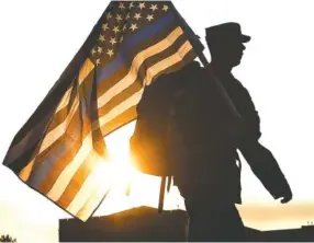  ?? STAFF PHOTO BY ROBIN RUDD ?? A UTC ROTC cadet carries an American flag past the rising sun, paying tribute to police officers lost on 9/11. On Wednesday, students and staff of the Military Science Department at the University of Tennessee at Chattanoog­a continuous­ly circled Chamberlai­n Field on the University’s campus from 6 a.m. to 5 p.m. in commemorat­ion of the 2001 terrorist attacks.