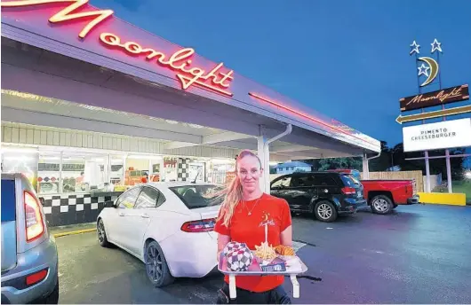  ?? STEPHEN M. DOWELL/ORLANDO SENTINEL ?? Carhop Jillian Mooreland holds a tray of food at the Moonlight Drive-In in Titusville on Sept. 22.