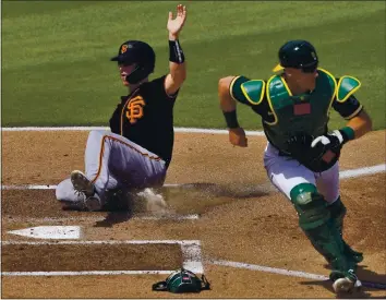  ?? MATT YORK — THE ASSOCIATED PRESS ?? The Giants’ Buster Posey scores on a hit by Mauricio Dubon as Athletics catcher Sean Murphy chases an off-line throw during the first inning of a Cactus League game on Monday in Mesa, Ariz. San Francisco defeated Oakland, 7-2.