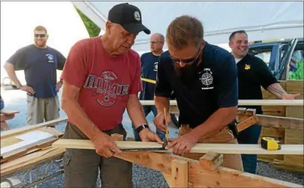  ?? TANIA BARRICKLO — DAILY FREEMAN ?? Art Russell of Saugerties, left, measures a board with Kevin Shorette of Saugerties while participat­ing in the Veterans Wooden Boat Workshop at the Rondout Yacht Basin in Connelly. In the rear, from left, are veterans Bill Carr of Kingston, co-founder Kevin Keaveny and Russell’s son Matthew, also of Saugerties.