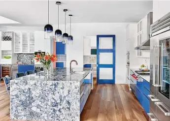  ?? ?? Bright blue cabinets and modern pendants make the kitchen stand out.