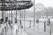  ?? BRENDAN SMIALOWSKI/GETTY-AFP ?? People pass an empty merry-go-round and the closed Smithsonia­n Natural History Museum on Saturday.