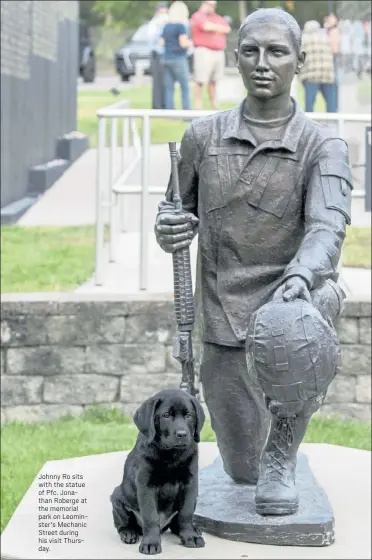  ??  ?? Johnny Ro sits with the statue of Pfc. Jonathan Roberge at the memorial park on Leominster's Mechanic Street during his visit Thursday.