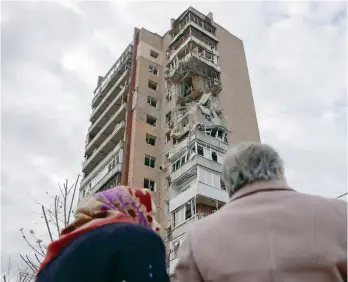  ?? — Reuters ?? Local residents stand in front of an apartment building hit by a Russian drone strike in Kharkiv, Ukraine.