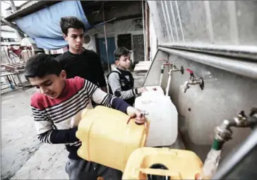  ?? SAID KHATIB/AFP ?? Palestinia­n youths fill bottles and jerricans with drinking water from public taps at the Rafah refugee camp in southern Gaza Strip last month.