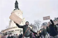  ??  ?? Two men holding signs reading “Free hugs” stand at Place de la Republique (Republic Square) in Paris yesterday as people gather to pay tribute to the victims of the Nov 13 terror attacks. —AFP