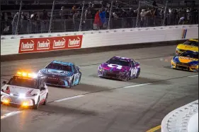  ?? Mike Caudill The Associated Press ?? Martin Truex Jr. leads as he lines up behind the safety car Sunday night as drivers await a restart at Richmond Raceway.