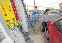  ??  ?? ASSOCIATED PRESS Lucy Perez pumps gas at a station in Matthews, N.C. Experts are predicting very low gas prices later this year as oil prices fall.