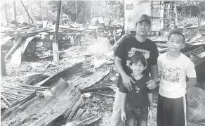  ??  ?? MOHON BANTUAN: James (kiri) bersama dua anaknya hanya mampu melihat rumah mereka yang terbakar.