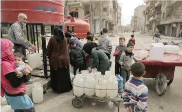  ?? — AFP ?? Syrians stand in queue next to a water reservoir in the once rebel-held Shaar neighbourh­ood in Aleppo.