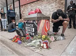  ?? ELIZABETH FLORES/STAR TRIBUNE ?? Mourners pray at a makeshift memorial Tuesday near where a man was taken into custody in Minneapoli­s. The death drew comparison­s to the case of Eric Garner.