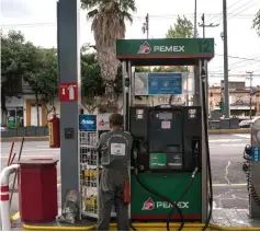  ?? WP-Bloomberg photos ?? (Left to right) An attendant fuels a taxi while counting money at a Petroleos Mexicanos (Pemex) gas station in Mexico City on Aug 6 and an attendant stands next to a fuel pump at a Petroleos Mexicanos (Pemex) gas station in Mexico City. —
