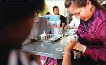  ?? TANG CHHIN SOTHY/AFP ?? A health official takes a blood sample from a villager during a screening for HIV in Kandal province last year.