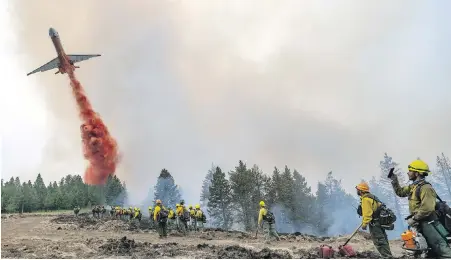  ?? LEWISTON TRIBUNE VIA AP ?? Wildland firefighte­rs watch and take video with their cellphones as a plane drops fire retardant on Harlow Ridge above the Lick Creek Fire, southwest of Asotin, Washington. The fire, which started last Wednesday, has burned more than 50,000 acres in southeast Washington state.