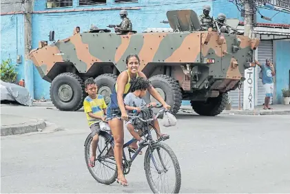  ?? EFE ?? Paseo. En bicicleta por la favela de Vila Aliança, con tanques del ejército vigilando las calles de la zona.