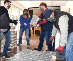  ?? NICK SMIRNOFF / FOR TEHACHAPI NEWS ?? Food is taken inside the building where its uncrated and stacked. Local Platinum Group volunteers Carson Wolff, Shannon Daffern and Christy Rabe put individual food items into family size food boxes.