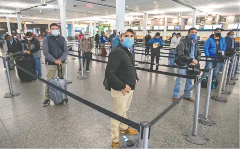  ?? RYAN REMIORZ / THE CANADIAN PRESS ?? Migrant workers from Mexico maintain social distancing as they wait to be transporte­d to Quebec farms after arriving Tuesday at Trudeau Airport.