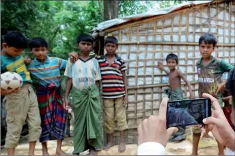  ?? — AFP photos ?? Children pose as Rafiq takes their photos with a mobile phone at the Kutupalong refugee camp.