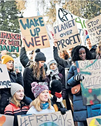  ??  ?? Greta Thunberg, standing centre in scarf, with other young environmen­tal campaigner­s at a demonstrat­ion in the heart of Davos