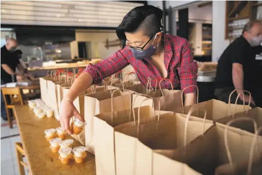  ?? Photos by Santiago Mejia / The Chronicle ?? Joyce Liu of the restaurant­s Quince and Cotogna places sauces into bags for the meal project at Verjus.