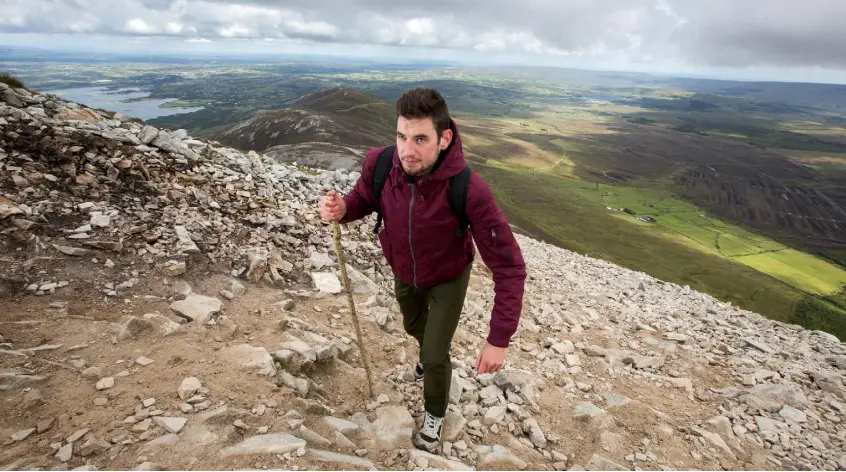  ??  ?? THE PATH OF TIME: Journalist Wayne O’Connor climbing Croagh Patrick in Co Mayo last week. Below: John Cummins is the sacristan at St Patrick’s Oratory on the peak of the mountain. Photos: Mark Condren