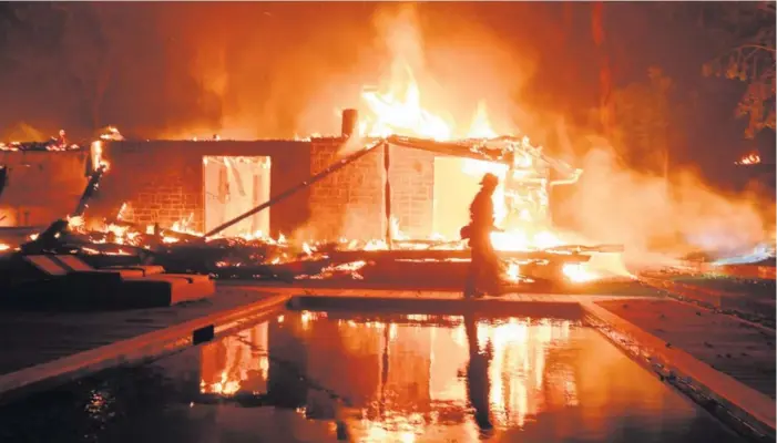  ?? AP ?? Un bombero camina frente a las ruinas de una casa en Malibú, California. Los incendios en el sur del estado continúan avanzando hacia la costa ayudados por el viento.